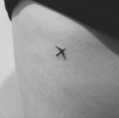 a black and white photo of a small airplane tattoo on the side of a woman's thigh