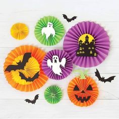 paper fans decorated with halloween decorations on a white wooden surface, including bats and pumpkins