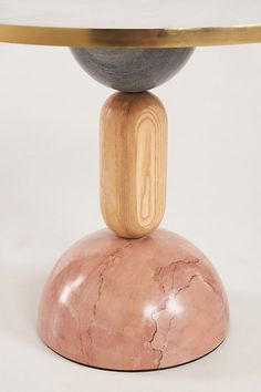 a round table with a marble top and two wooden posts on each end, in front of a white background