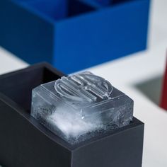 an ice cube sitting on top of a black box next to red and blue boxes