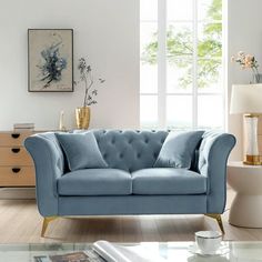 a blue couch sitting in a living room next to a window