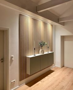 an empty room with a vase and flowers on the counter in front of a wooden paneled wall