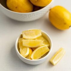 a bowl full of lemons next to some cut up lemons