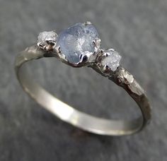 a white gold ring with three diamonds on the top and one stone in the middle