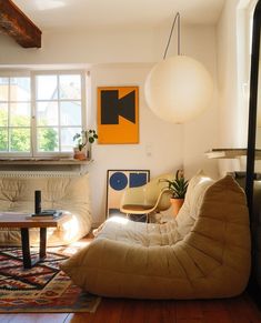 a living room filled with furniture and a lamp hanging from it's ceiling over a wooden floor