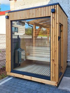 a small wooden sauna with glass doors on the outside and brick walkway in front