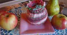 there are three apples and two pears on the table, one has a knitted bag