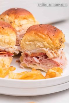 two ham and cheese sliders on a white plate with potato chips next to it