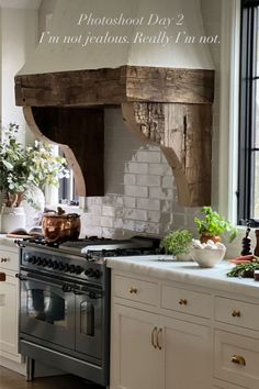 a kitchen with white cabinets and an old fashioned stove in the center, surrounded by potted plants