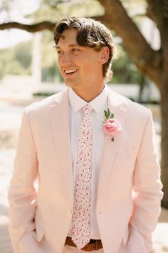 a man wearing a pink suit and flower tie