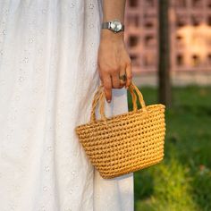 a woman in white dress holding a yellow basket with handles on her left hand and wearing a watch