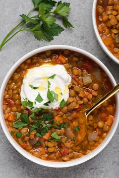 two white bowls filled with beans and sour cream, garnished with parsley