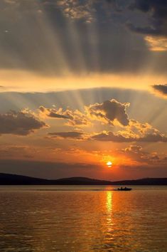 the sun is setting over water with boats in it