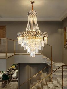 a chandelier hanging from the ceiling in a living room with stairs and tables