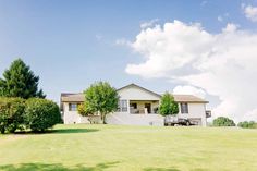 a large white house sitting on top of a lush green field under a blue sky