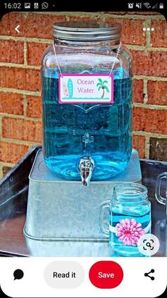 a glass jar filled with blue water sitting on top of a metal tray next to a brick wall