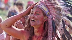 a woman with red paint on her face and headdress is smiling at the camera