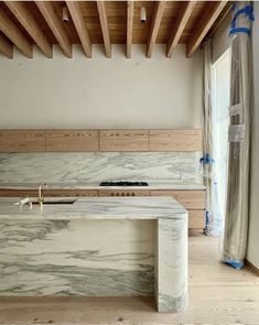 a kitchen with marble counter tops and wooden ceiling beams in the middle of the room