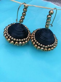 pair of black and gold beaded earrings on a blue surface with string attached to it