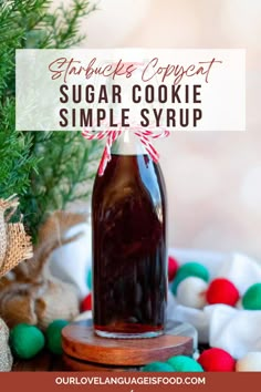 a homemade sugar cookie syrup recipe in a glass bottle on a wooden board with christmas decorations around it