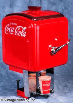 an old fashioned coca cola machine with two cups