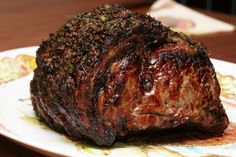 a large piece of meat sitting on top of a yellow and white plate covered in sauce