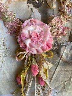 a bouquet of pink flowers sitting on top of a piece of paper covered in lace