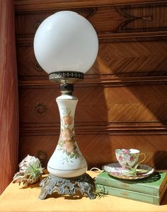 a white lamp sitting on top of a table next to a cup and saucer