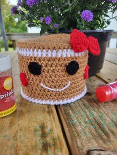 a crocheted cup with a face on it sitting next to a flower pot