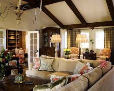 a living room filled with furniture and a chandelier hanging from a wooden ceiling