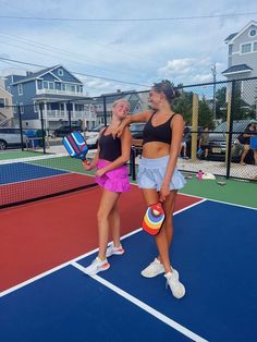 two women standing on a tennis court holding racquets and ball in their hands