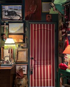 a room with pictures on the wall and a red striped door in front of it