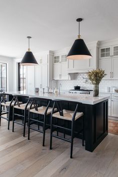 a kitchen with white cabinets and black chairs