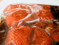 salmon wrapped in plastic sitting on top of a cutting board