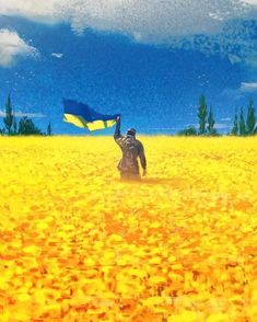 a man walking through a field with a flag in his hand and yellow flowers on the ground