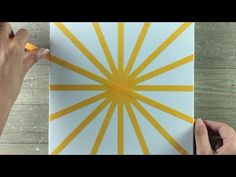 someone is using yellow tape to create a sunburst design on a piece of paper