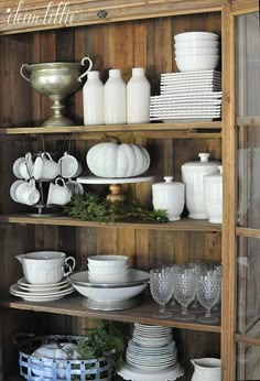 a wooden shelf filled with white dishes and plates on top of it's sides