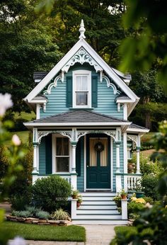 a blue house with white trim and green shutters on the front door is surrounded by greenery