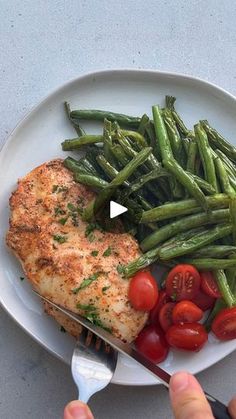 someone cutting up some food on a plate with a knife and fork next to it