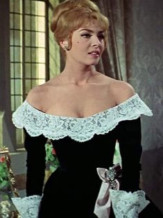 the woman is wearing a black dress with white lace trims on her shoulders and shoulder