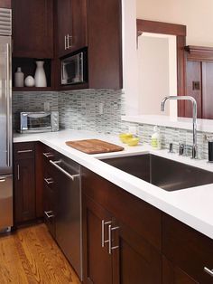 a kitchen with brown cabinets and white counter tops, stainless steel appliances and wooden flooring