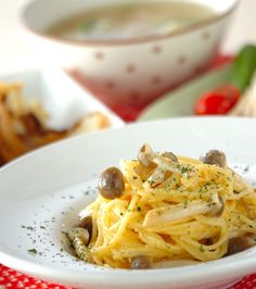 a white bowl filled with pasta and mushrooms on top of a red checkered table cloth