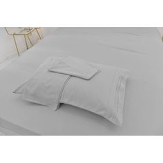 a bed with white sheets and pillows on it