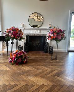 flowers are arranged on the floor in front of a fireplace and mirror above it is a piano