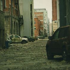 two cars are parked on the side of an alleyway in front of tall buildings