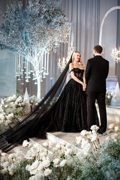 a man and woman standing next to each other in front of a wedding dress on display