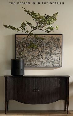 a potted plant sitting on top of a wooden cabinet in front of a painting