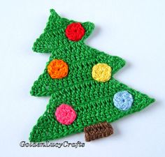 a crocheted christmas tree ornament on a white surface with red, yellow, blue and green balls