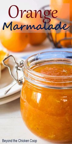 an orange marmalade in a glass jar on a white table with plates and utensils