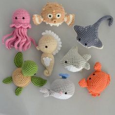 crocheted sea animals are arranged on a white surface, including an octopus, fish, and squid